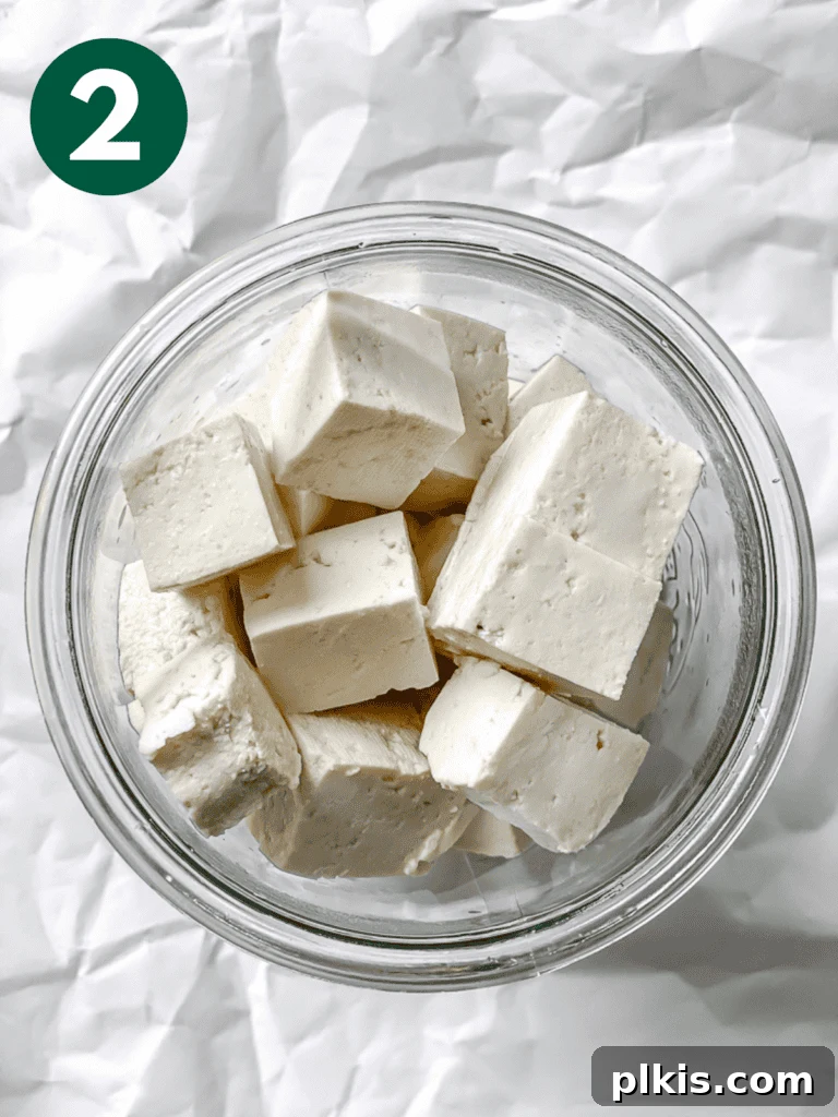Process shot showing cubed tofu being added to a jar with the prepared brine