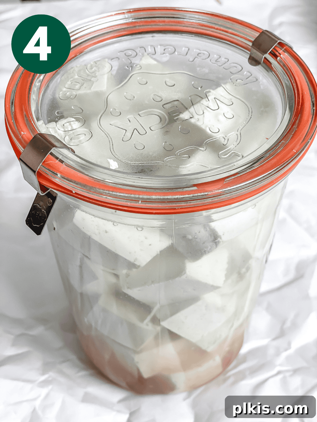 Process shot showing tofu feta cheese marinating in a jar in the refrigerator