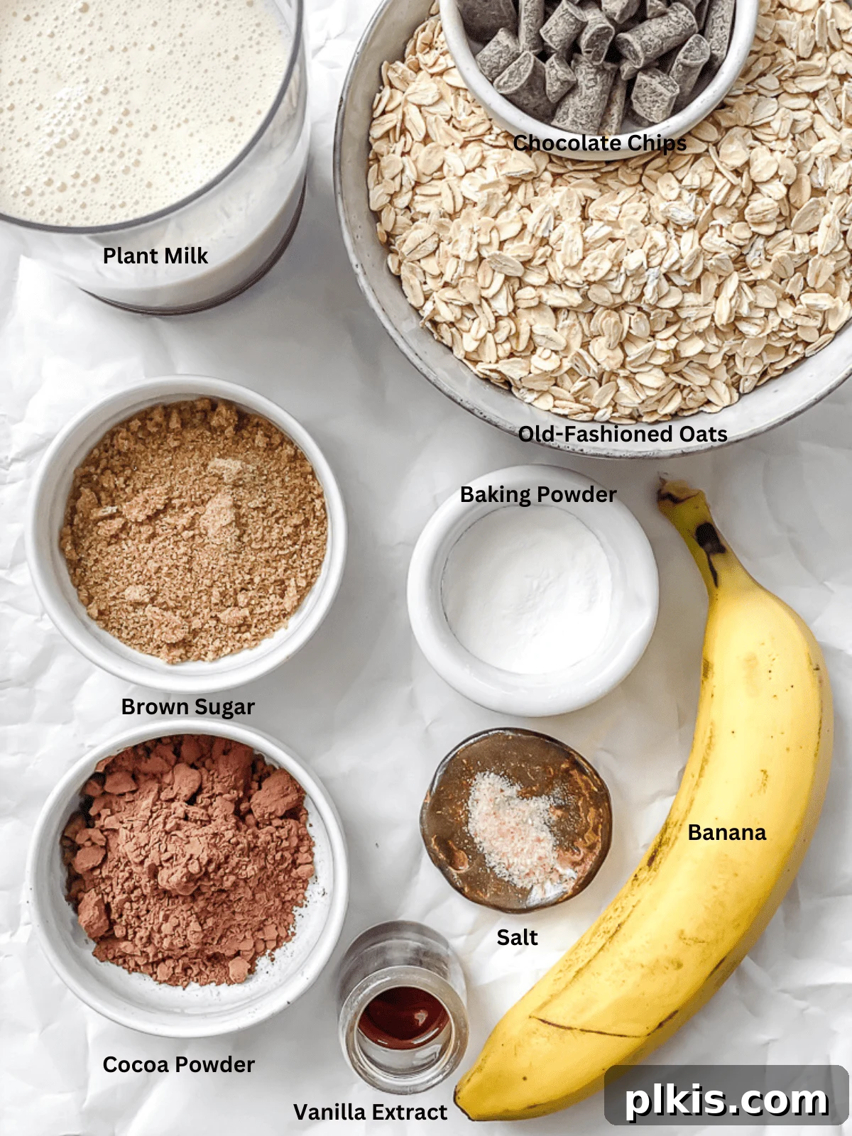 Decadent Chocolate Baked Oats: Smooth or Hearty 3 Various ingredients for Chocolate Baked Oatmeal, including oats, bananas, milk, cocoa powder, and chocolate chips, neatly laid out on a surface
