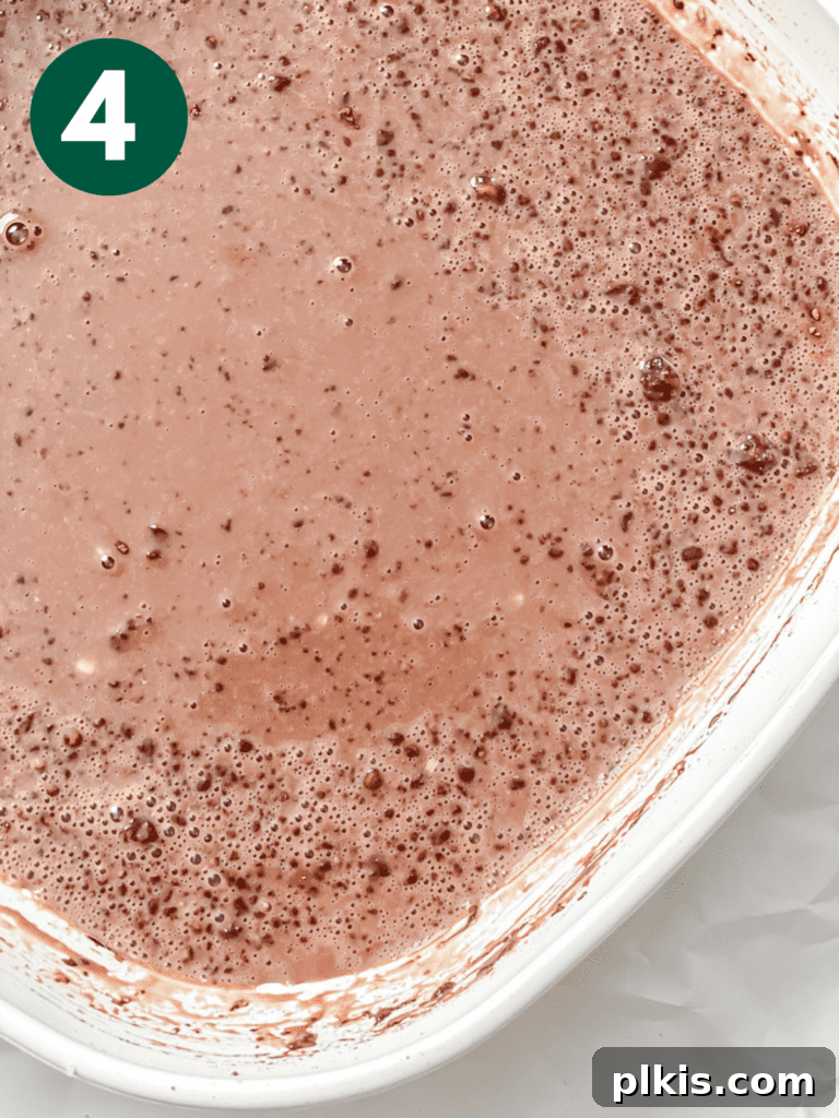 Decadent Chocolate Baked Oats: Smooth or Hearty 7 Process shot showing cocoa powder being added to the wet ingredients in the dish