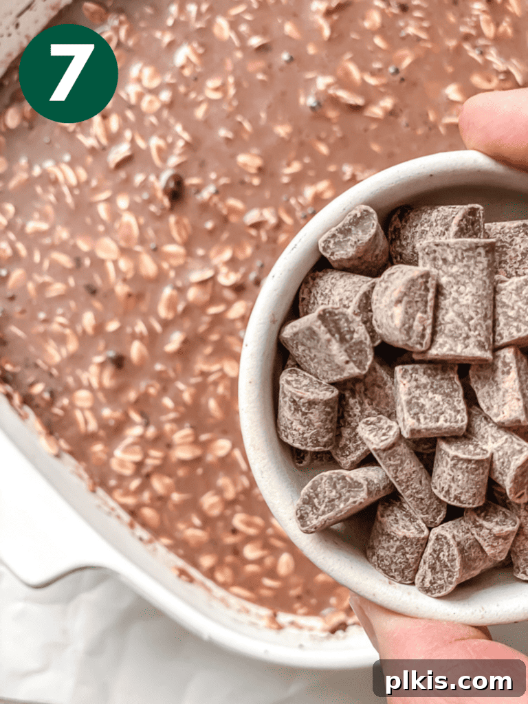Decadent Chocolate Baked Oats: Smooth or Hearty 10 Process shot showing vegan chocolate chunks being added as a topping to the oat mixture