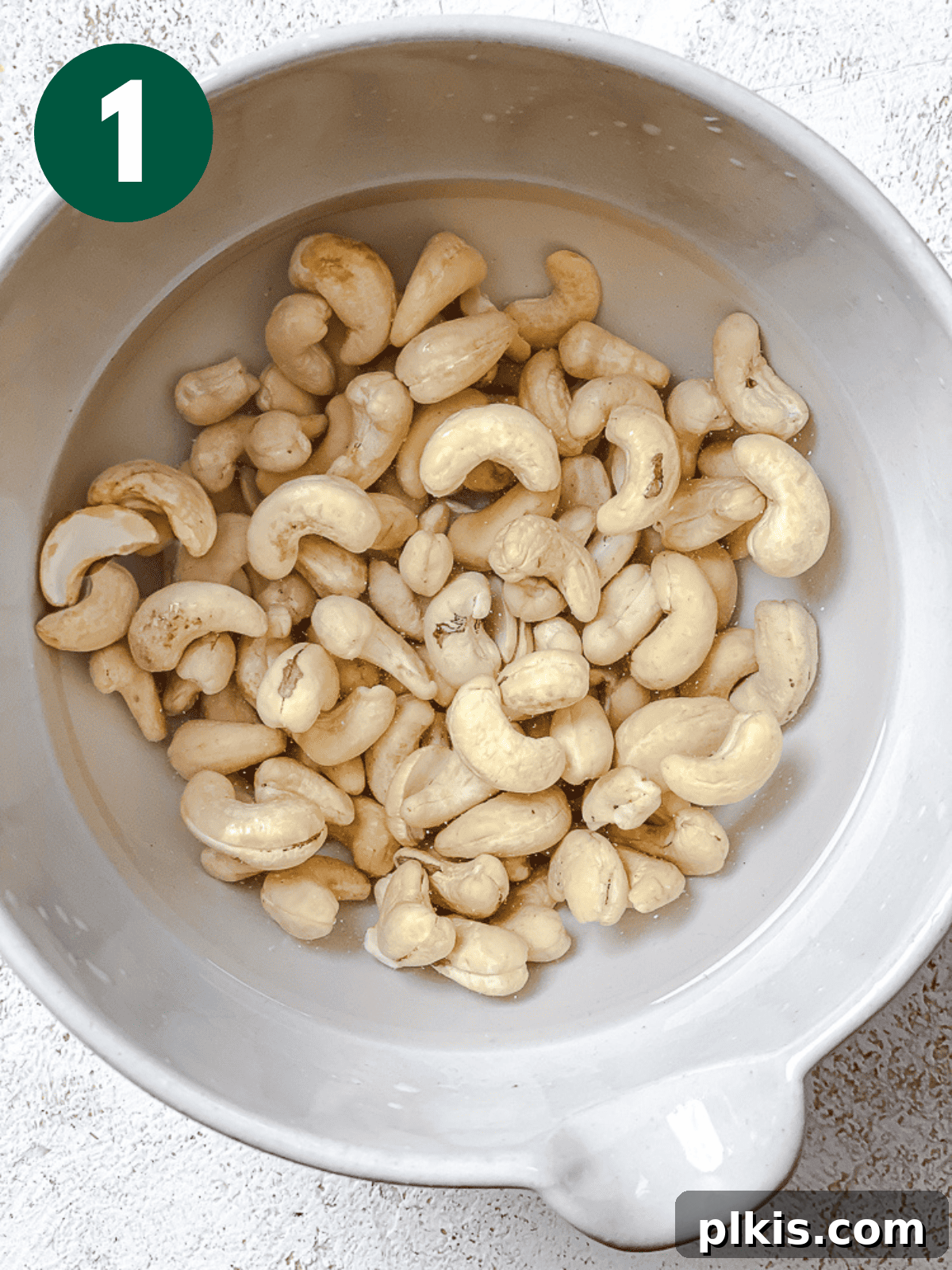 Silky Cashew Cream 4 raw cashews soaking in water in a large white bowl.