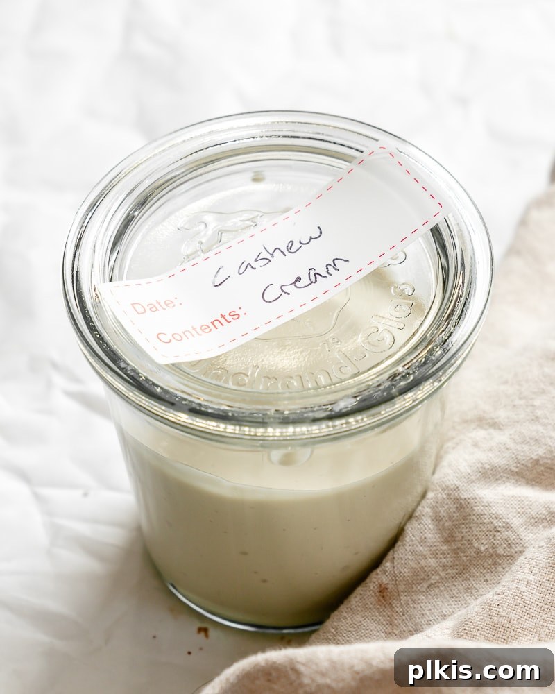 Silky Cashew Cream 9 cashew cream in a clear glass jar with a handwritten label, ready for storage.