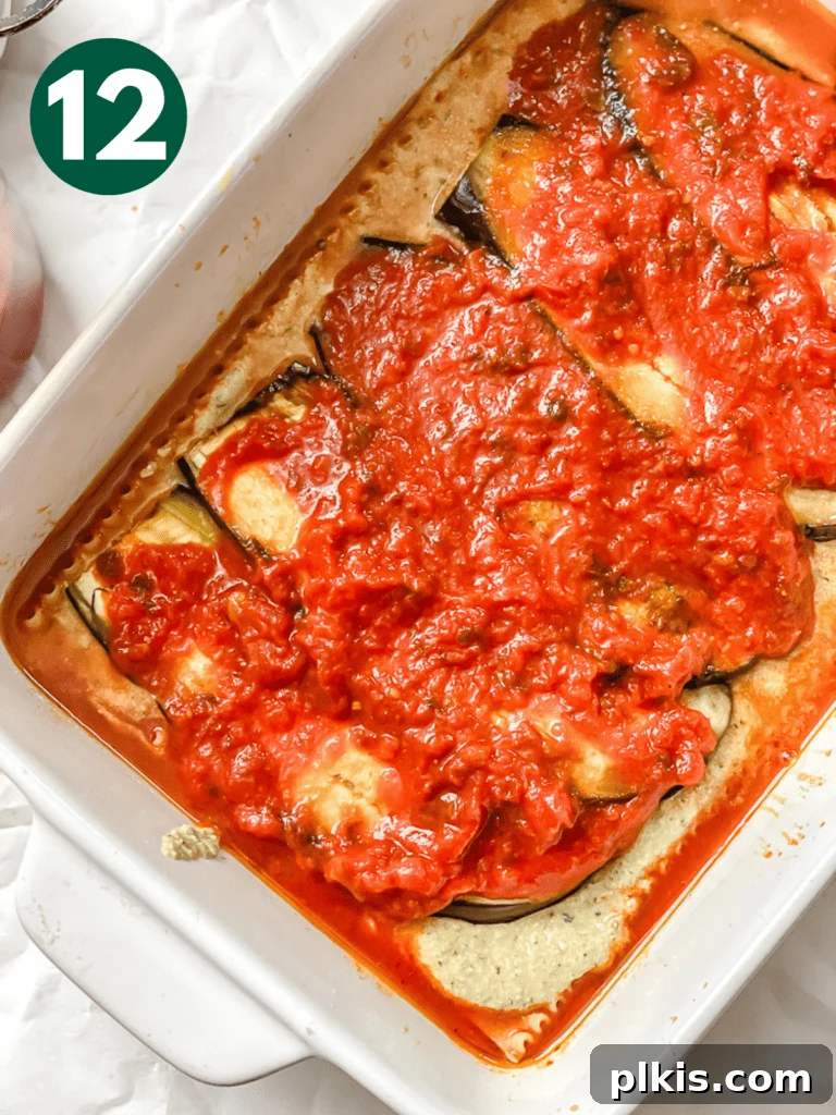 Hearty Vegan Eggplant Lasagna 15 A vibrant layer of tomato basil sauce poured over the tofu ricotta and eggplant in the vegan lasagna assembly.
