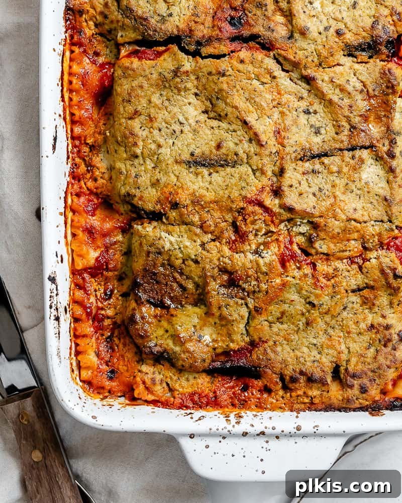 Hearty Vegan Eggplant Lasagna 24 A beautifully golden-brown and perfectly baked vegan eggplant lasagna, still in its baking dish, garnished with fresh herbs.