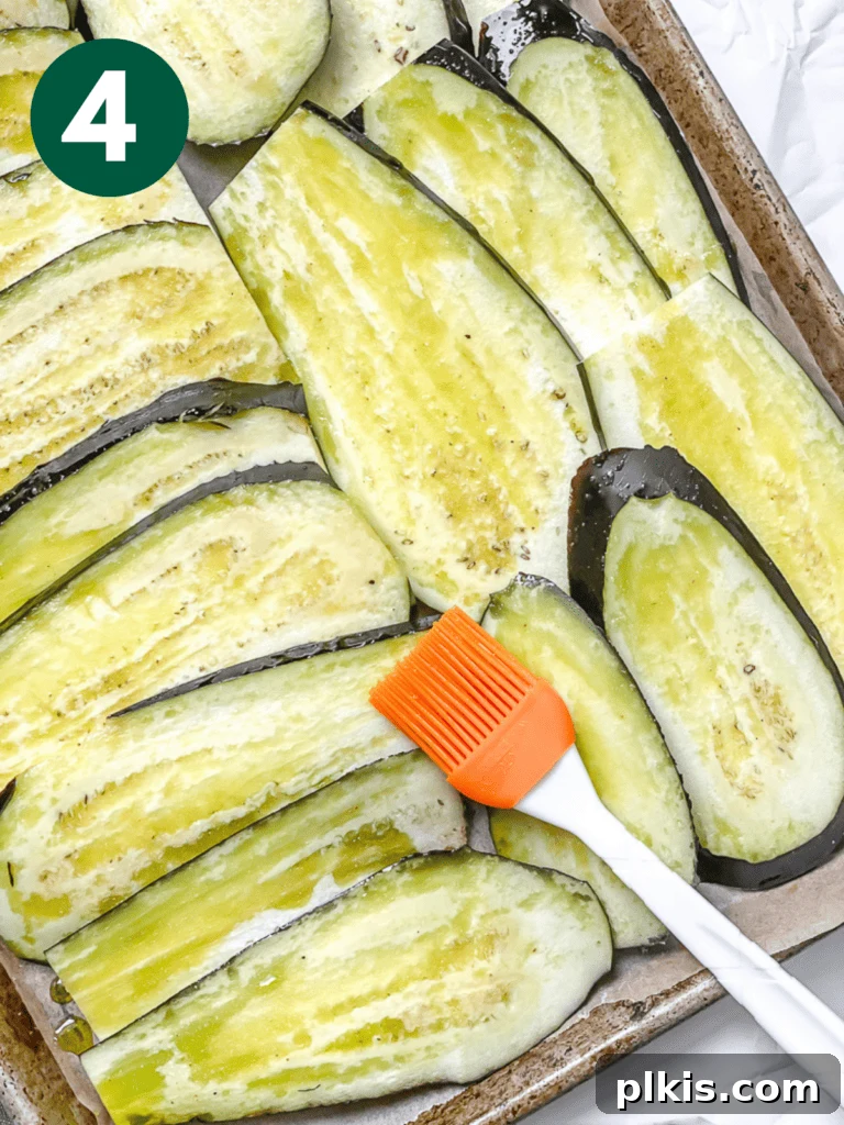 Hearty Vegan Eggplant Lasagna 7 Close-up of eggplant slices glistening with a light coat of olive oil and salt, ready for oven roasting.