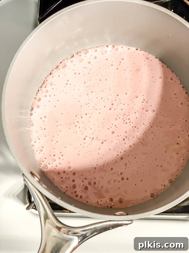 Process shot showing strawberry milk added to pot.