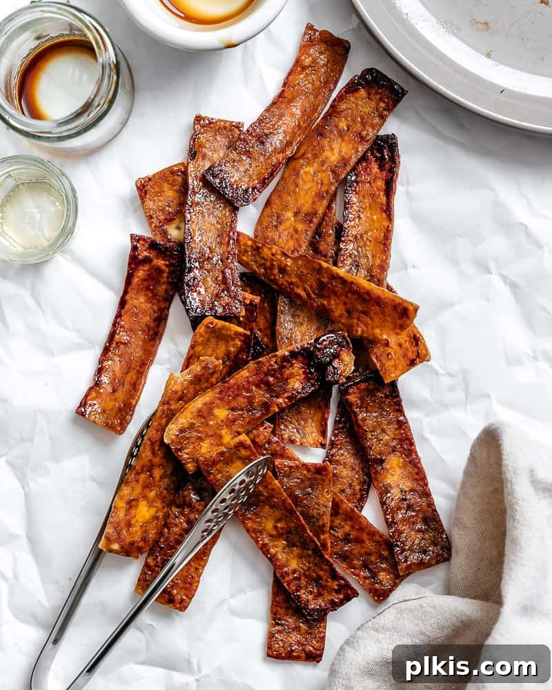 Golden Crispy Tofu Bacon 2 A pile of sauce-covered and baked vegan tofu bacon strips, ready to be enjoyed.