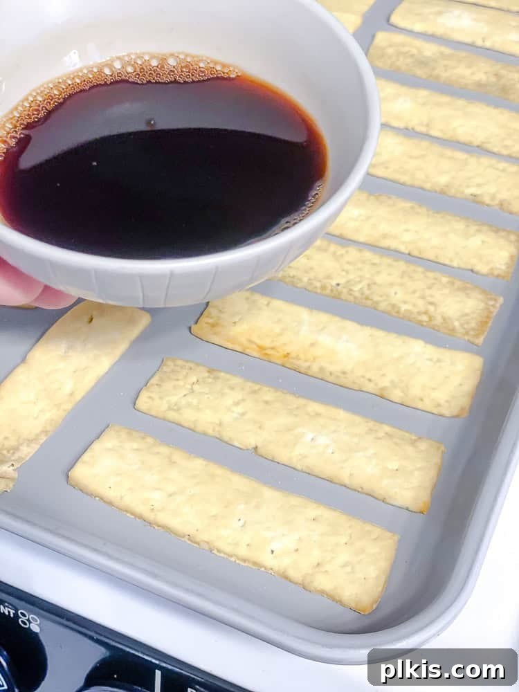 Golden Crispy Tofu Bacon 7 Process shot showing the prepared marinade being poured over the pre-baked tofu strips on a baking pan.