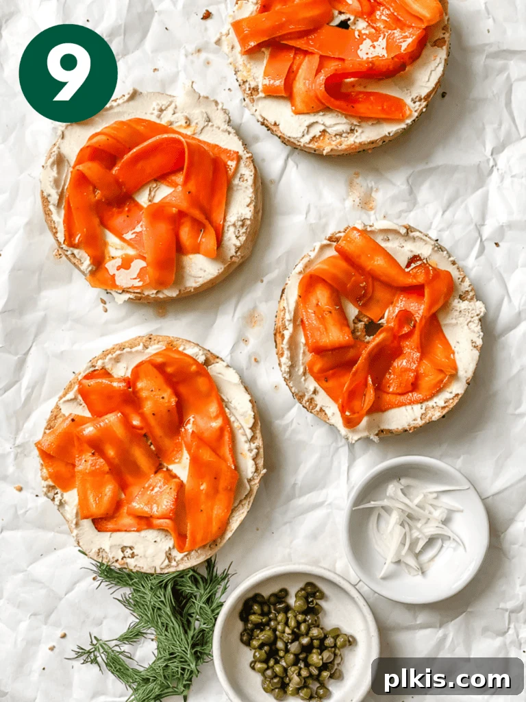 Smoky Carrot Lox 12 A beautifully assembled Carrot Lox bagel, complete with vegan cream cheese, capers, fresh dill, and thinly sliced shallots, resting on a white surface, showcasing the vibrant and appetizing vegan smoked salmon alternative.