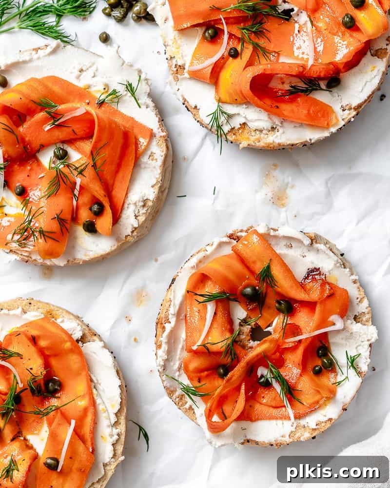 Smoky Carrot Lox 13 A striking image of completed Carrot Lox, showcasing its vibrant orange color and delicate texture, spread across two halves of a bagel with cream cheese, capers, and dill, presented on a clean white backdrop.