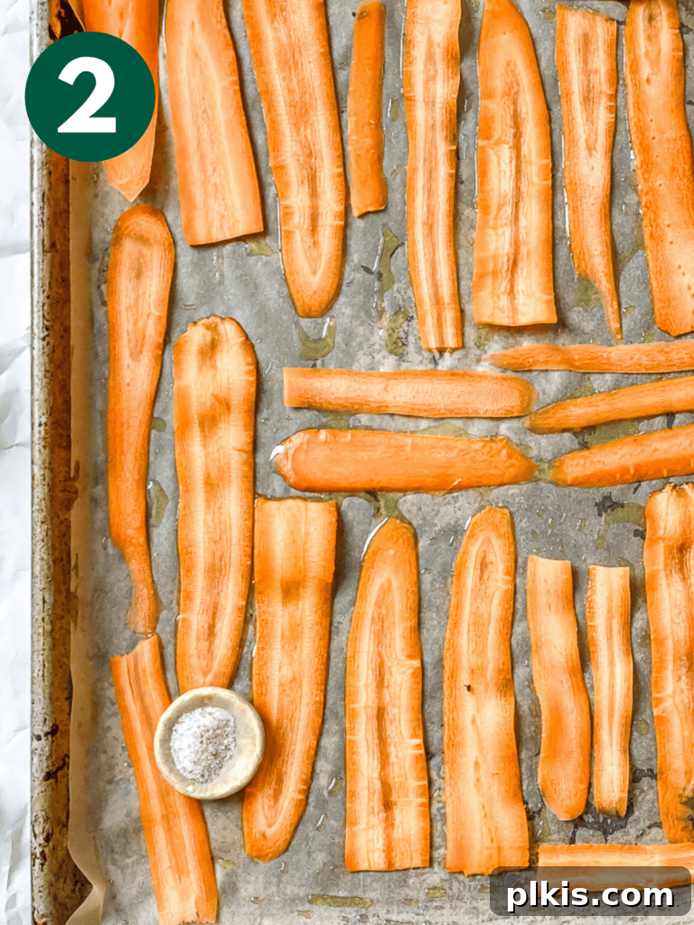 Smoky Carrot Lox 5 A process shot showing thin carrot ribbons neatly arranged in a single layer on a parchment-lined baking tray, ready for seasoning and marinade.