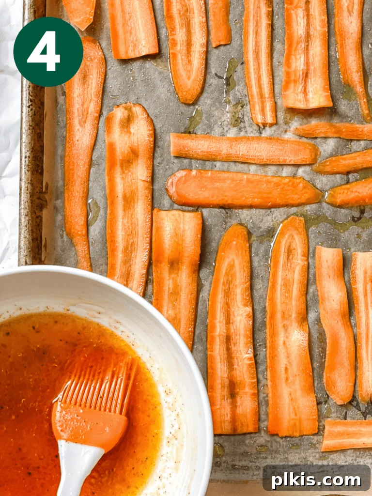 Smoky Carrot Lox 7 A process shot showing a bowl of prepared marinade positioned above a baking tray filled with carrot ribbons, ready to be brushed.
