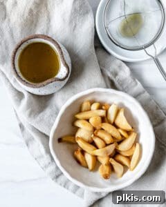 Stovetop Garlic Duo: Pan-Roasted & Confit 7 completed Stovetop Roasted Garlic in a white bowl against a white background with oil in the background