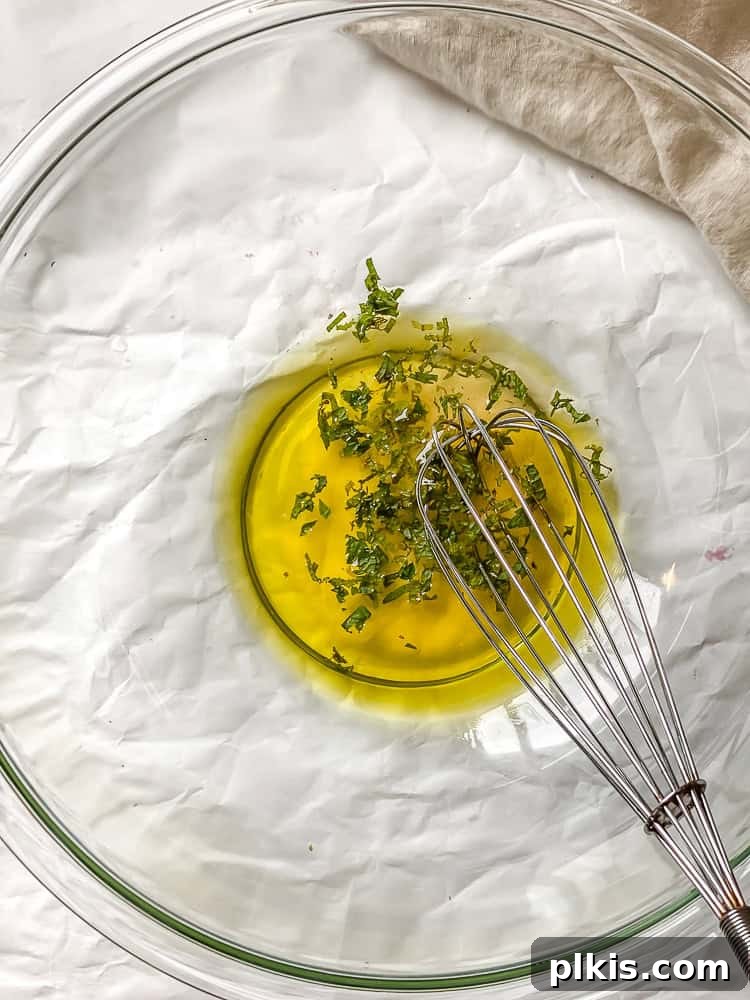 Process shot showing whisking salad dressing in a large glass bowl.