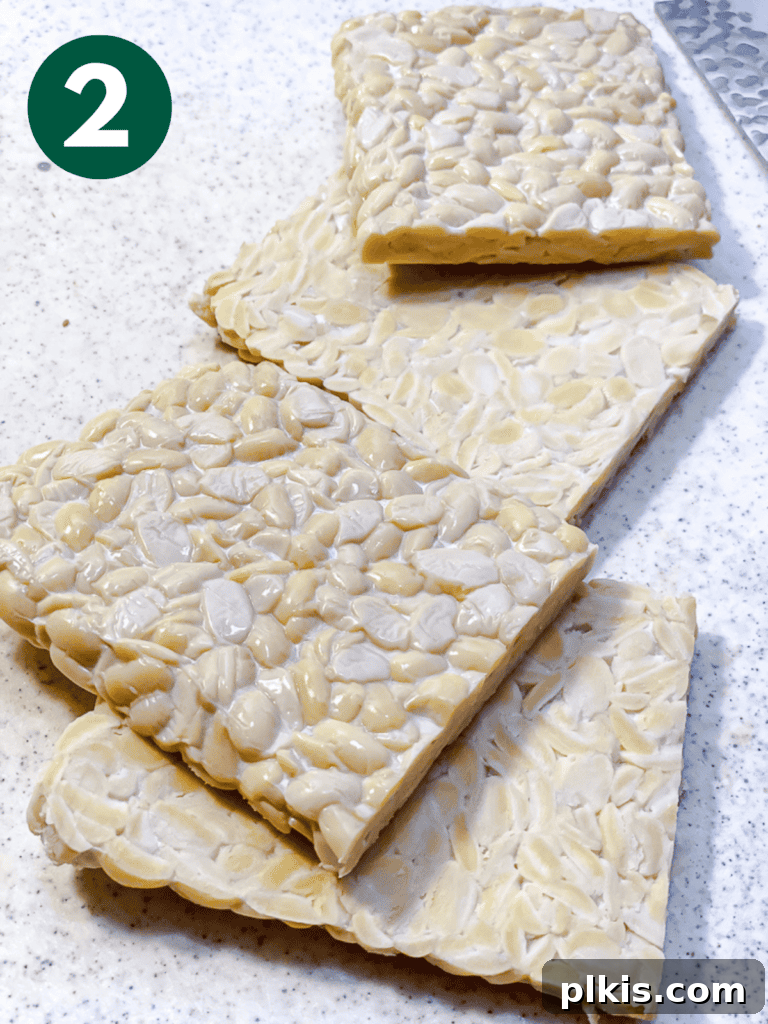 Savory Tempeh Sensation 5 Process shot showing a block of tempeh being sliced into four even slabs.