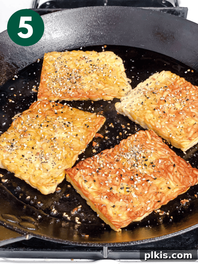 Savory Tempeh Sensation 8 Process shot showing cooked tempeh slices being flipped in a pan, ready for more seasoning.