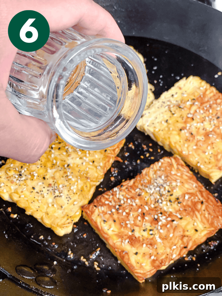 Savory Tempeh Sensation 9 Process shot showing water being added to the pan with tempeh slices, before covering with a lid.