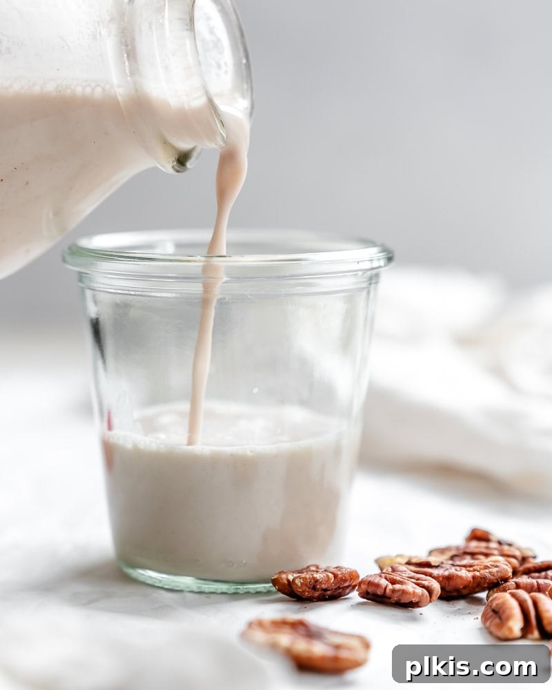 Freshly made pecan milk being poured into a glass, highlighting its creamy texture.