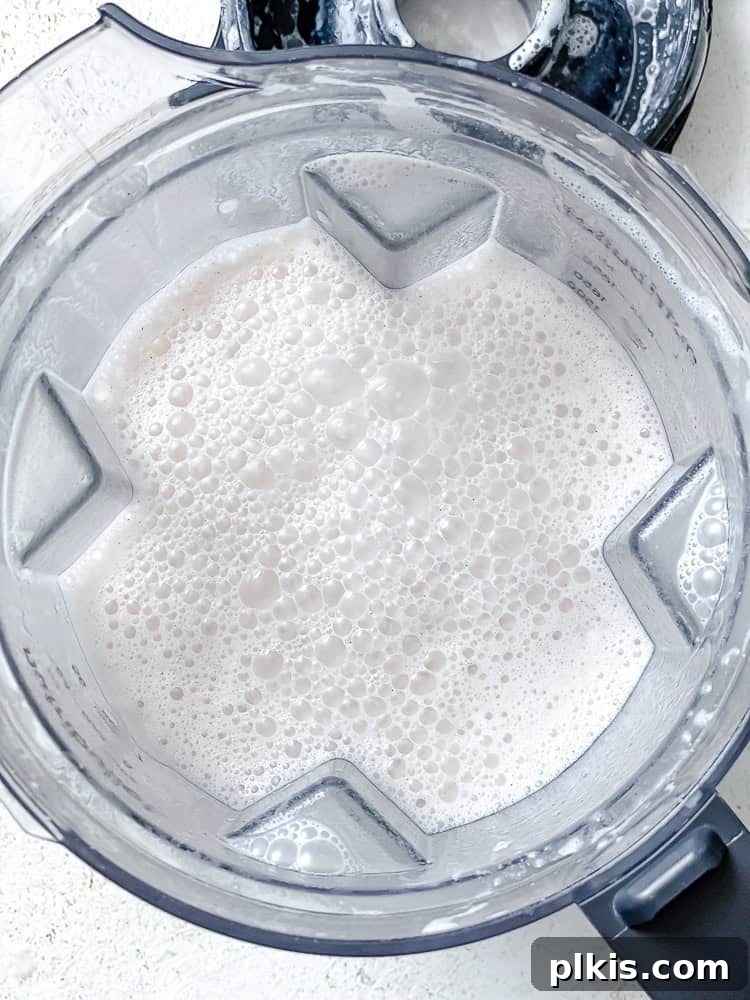 Blended pecan milk with a foamy top inside a high-speed blender, showing its creamy consistency.