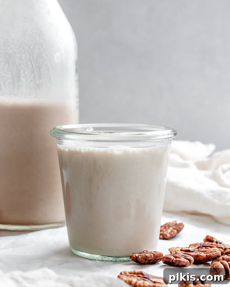 Two servings of homemade pecan milk, one in a glass jar and one poured into a cup, ready to be enjoyed.