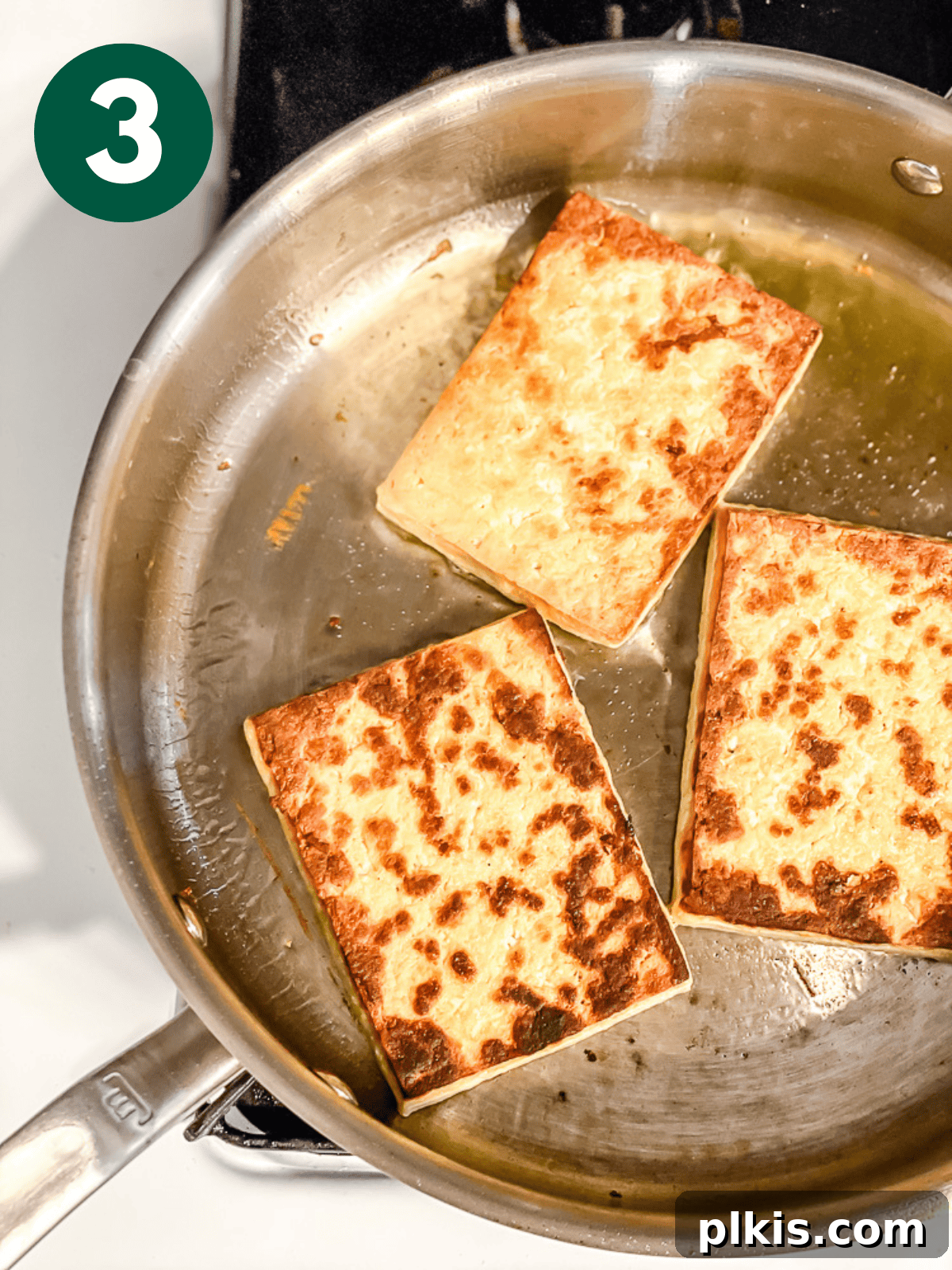 Chipotle Spiced Tofu 6 frying tofu slices in a large metal pan.