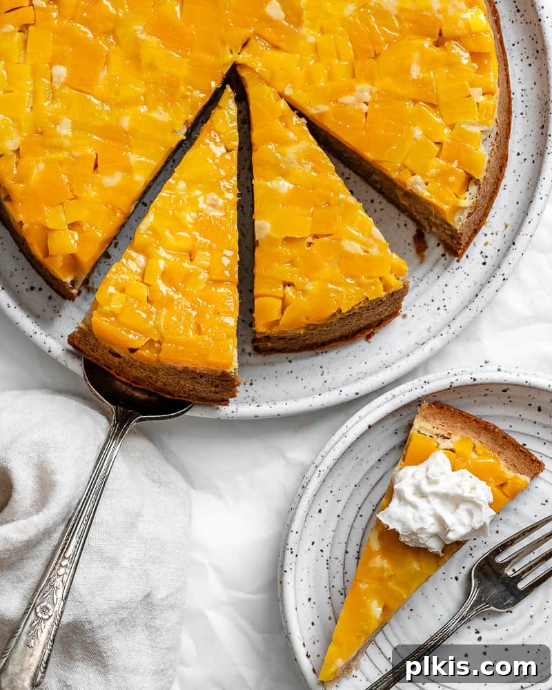 Tropical Mango Delight 2 a sliced mango cake next to a slice of cake on a small white plate, showcasing the vibrant mango topping.