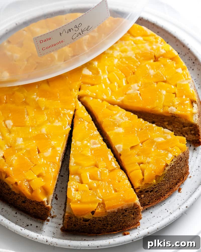 Tropical Mango Delight 18 sliced mango cake on a white plate with a storage lid on top, emphasizing freshness.
