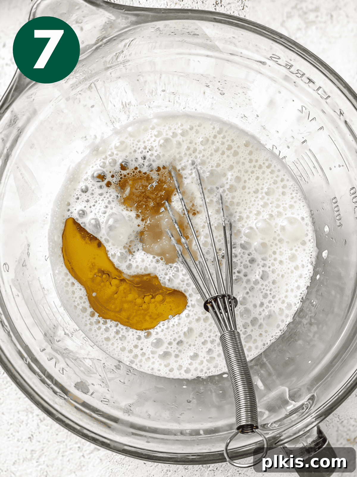 Tropical Mango Delight 10 whisking the wet ingredients for mango cake in a large glass bowl.