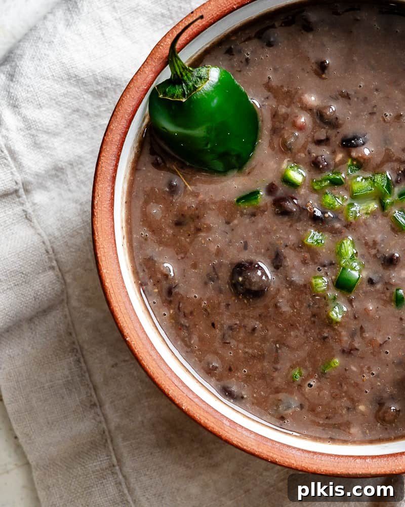 Spiced Black Bean Warmth 12 close up on black bean soup topped with diced jalapenos in a bowl.