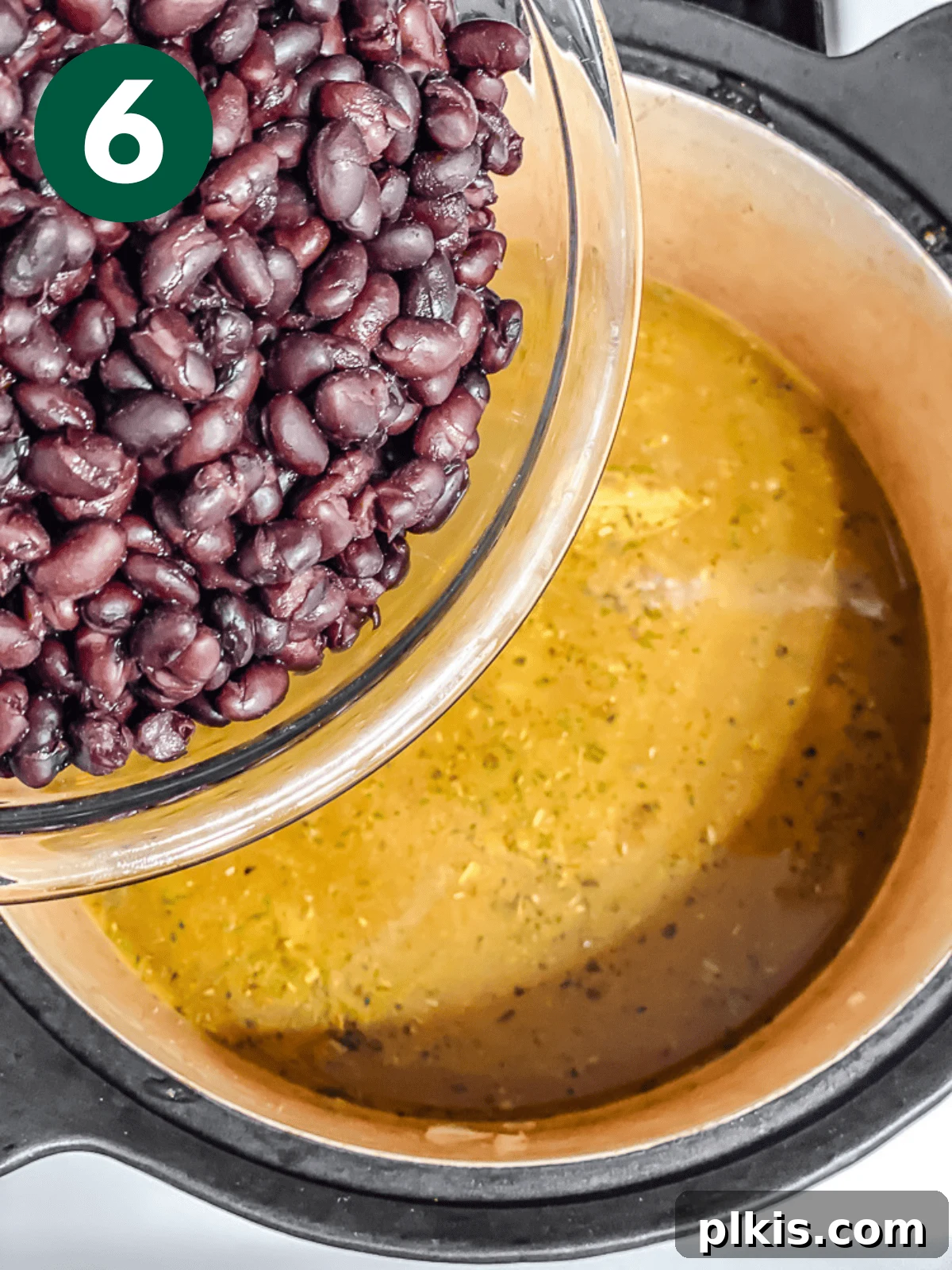 Spiced Black Bean Warmth 9 pouring black beans into soup in a large pot.