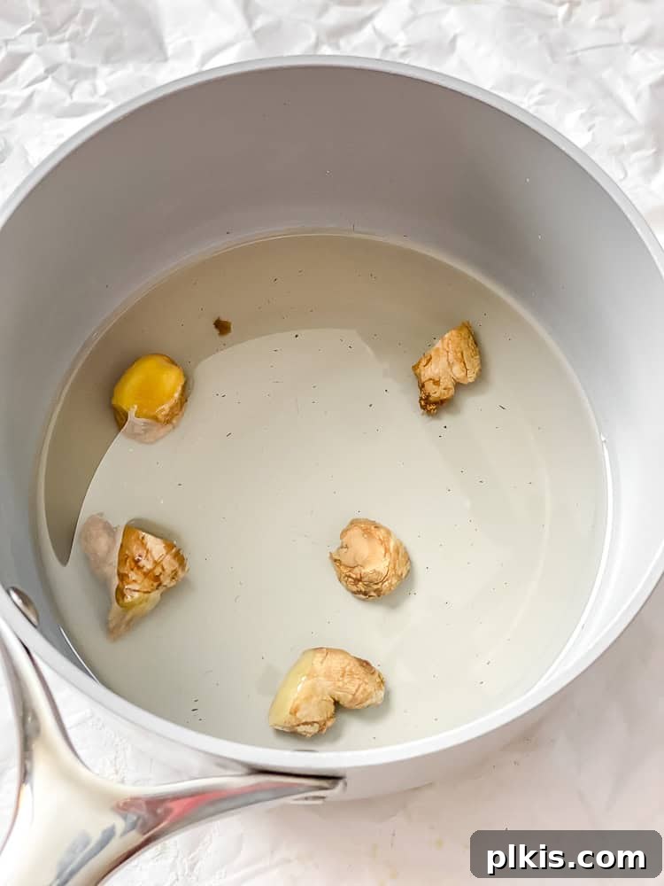 Crafting the Perfect Cup of Ginger Tea 5 Process shot showing sliced and crushed ginger root in a pot, ready for simmering.