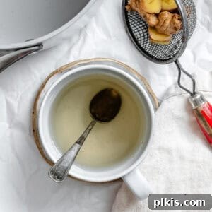 Crafting the Perfect Cup of Ginger Tea 8 A completed cup of ginger tea with a slice of lemon against a white background.