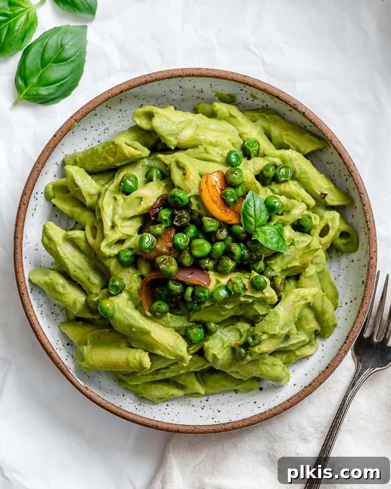 Emerald Pea Pasta 2 A vibrant bowl of creamy green pea pasta, garnished with fresh basil and red pepper flakes, ready to be enjoyed.