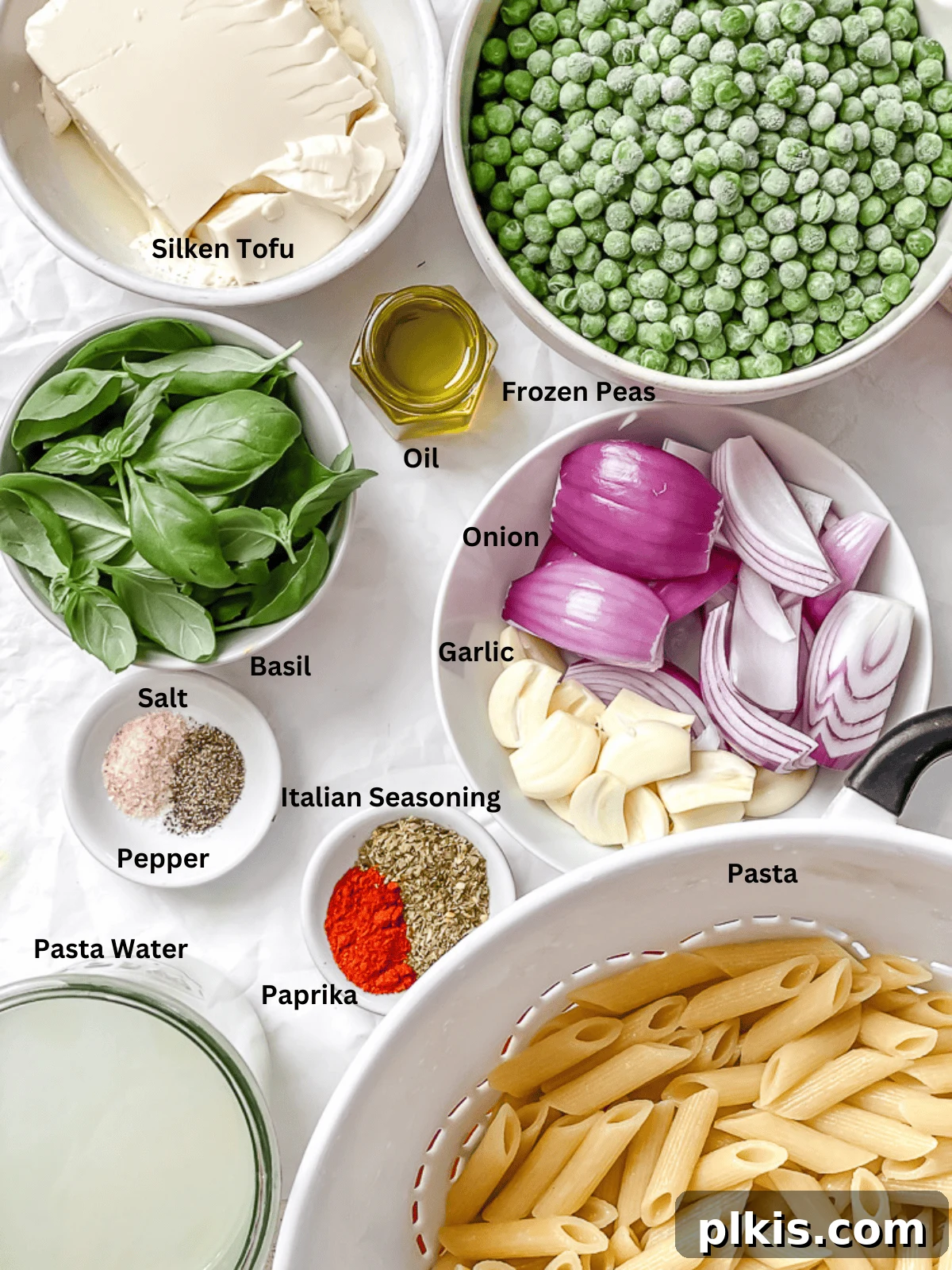 Emerald Pea Pasta 3 All the fresh ingredients for Green Pea Pasta laid out on a clean white surface, including peas, basil, tofu, garlic, and onion.