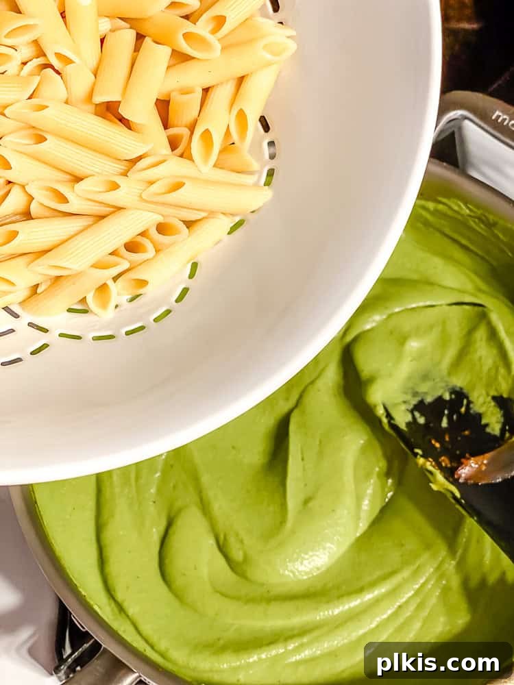 Emerald Pea Pasta 7 Process shot showing the cooked pasta being added to the creamy green pea sauce in a pan, ready to be tossed together.
