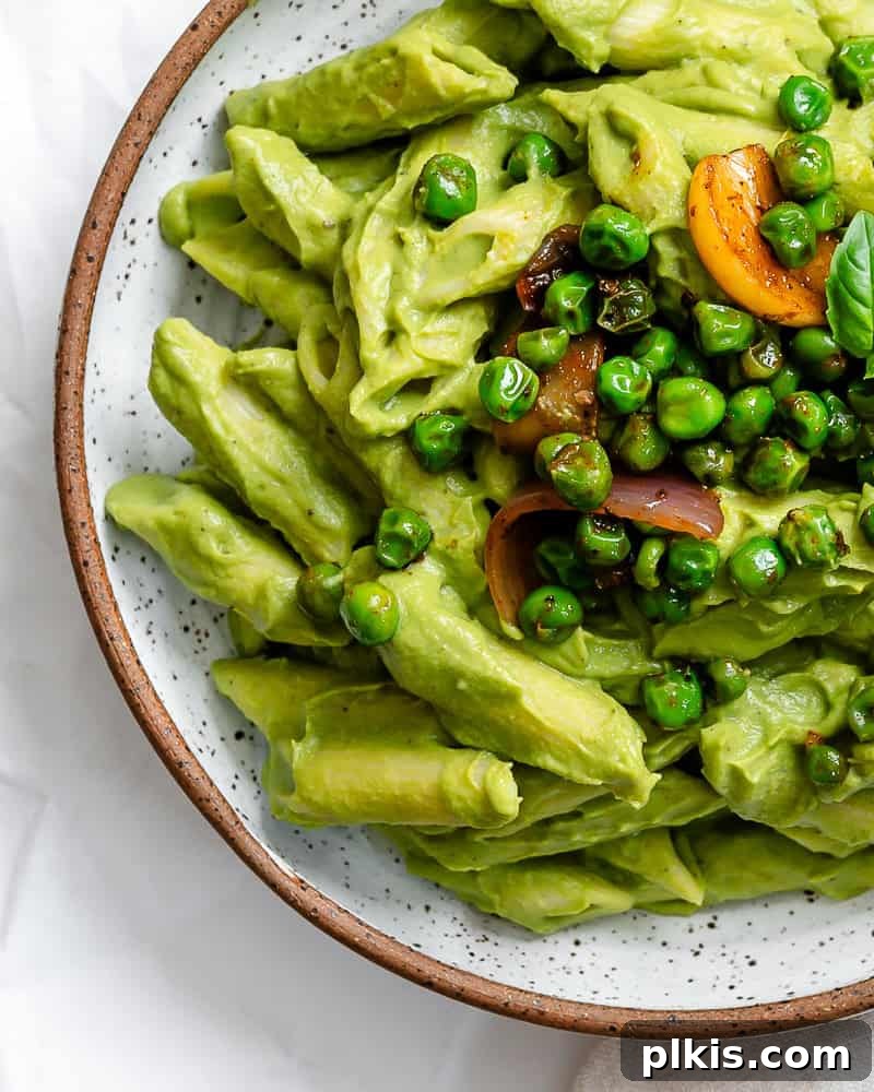 Emerald Pea Pasta 8 A beautifully plated portion of Green Pea Pasta, elegantly garnished with fresh basil, showcasing its vibrant green hue and creamy texture.