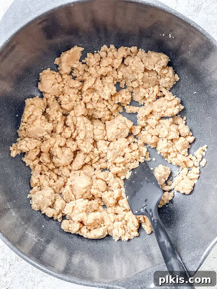 Process shot showing a bowl with crumble topping ingredients being stirred with a fork.