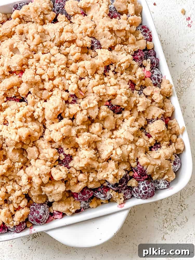 Process shot showing the unbaked blackberry crumble in a baking pan, ready for the oven.