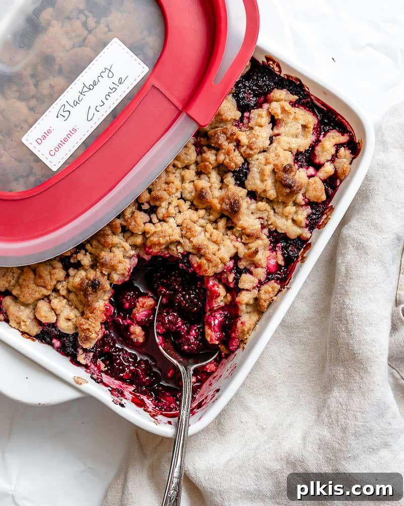 A dish of Easy Vegan Blackberry Crumble being stored in an airtight container, ready for the refrigerator or freezer.