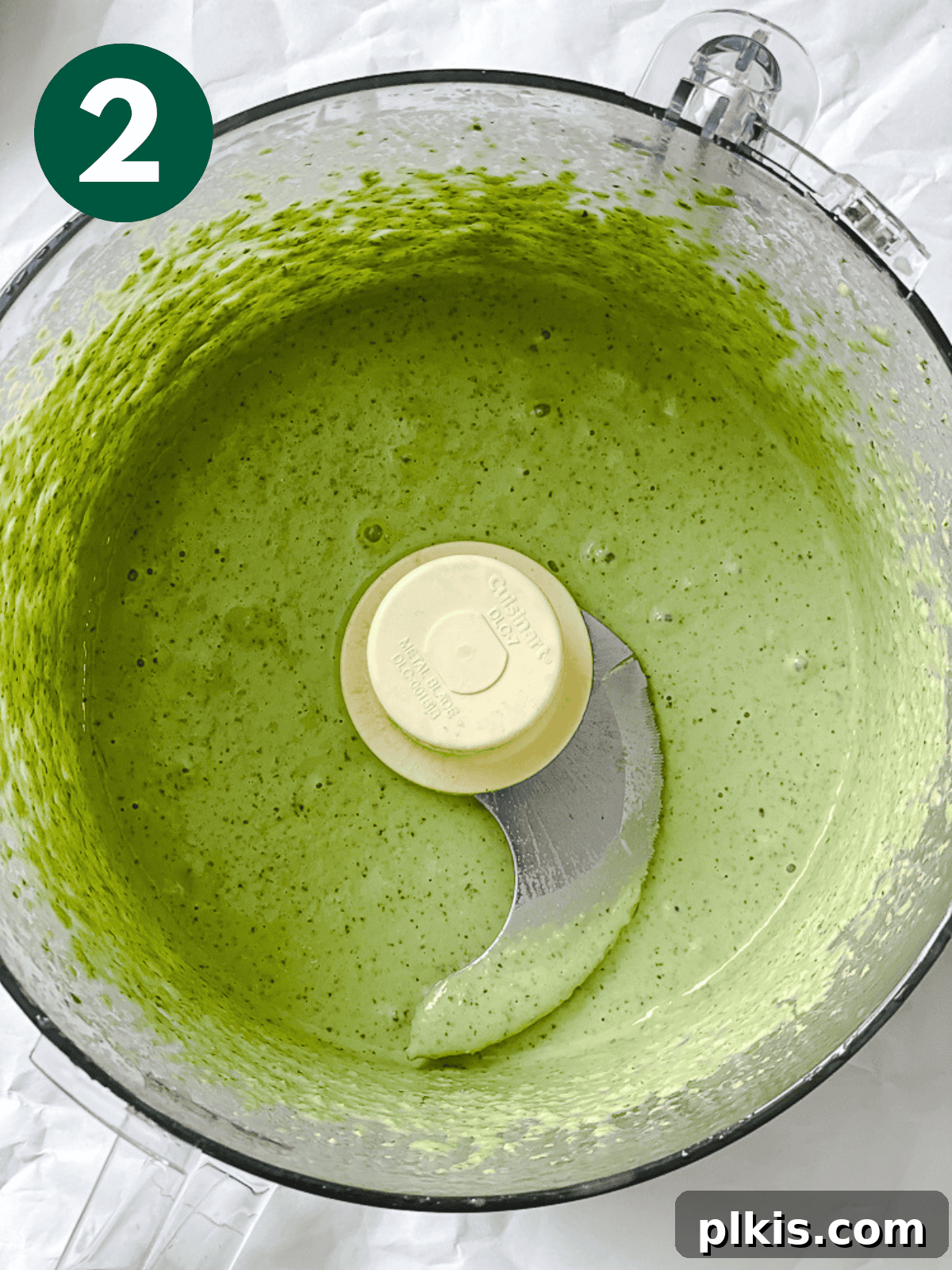 Smooth, blended vegan pesto visible inside a food processor.