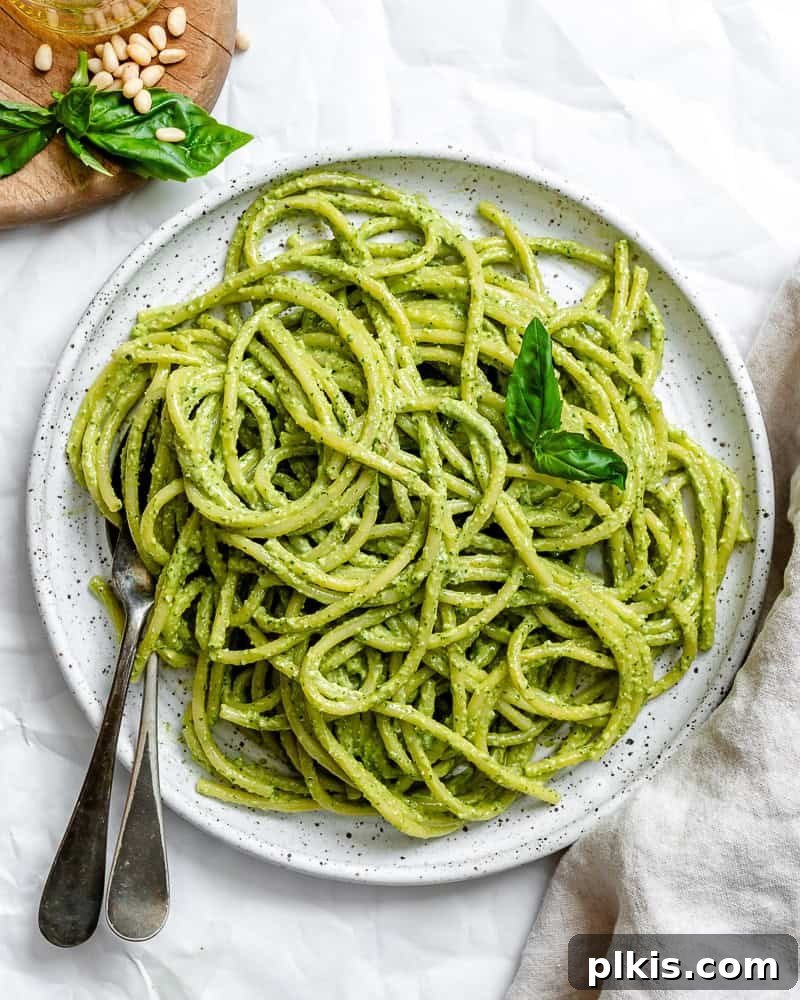 Vegan pesto pasta served on a white plate, garnished with fresh basil.