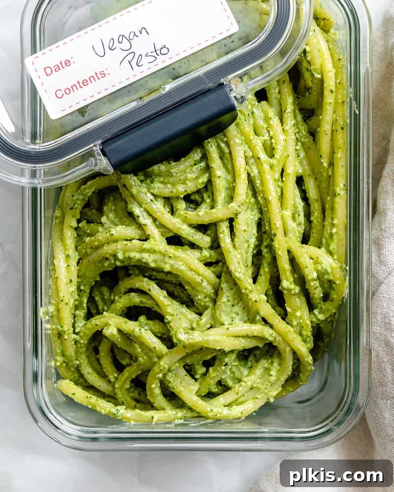 Leftover vegan pesto pasta stored in a clear glass container.