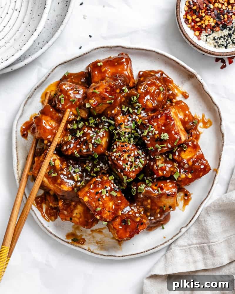 Crispy Tangy Tofu Delight 2 General Tso's tofu on a white plate with chopsticks on the side, ready to be enjoyed.