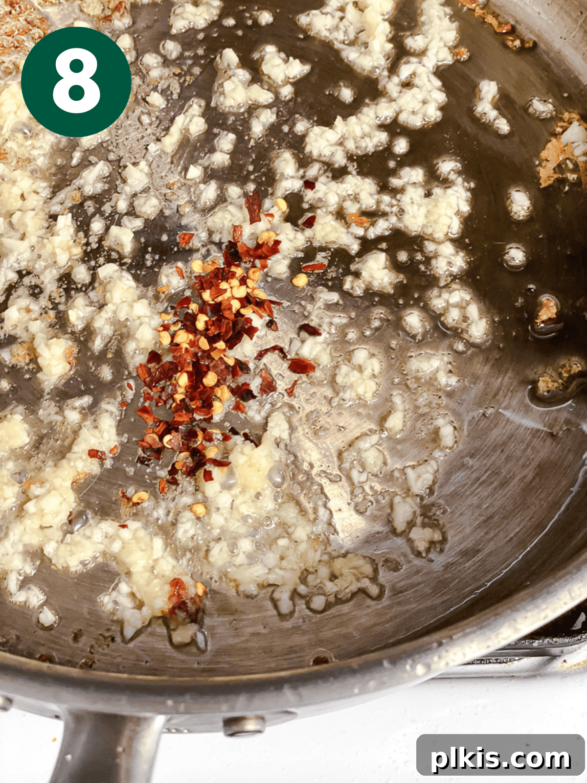 Crispy Tangy Tofu Delight 11 Minced ginger, garlic, and chili flakes frying in a large metal pan.