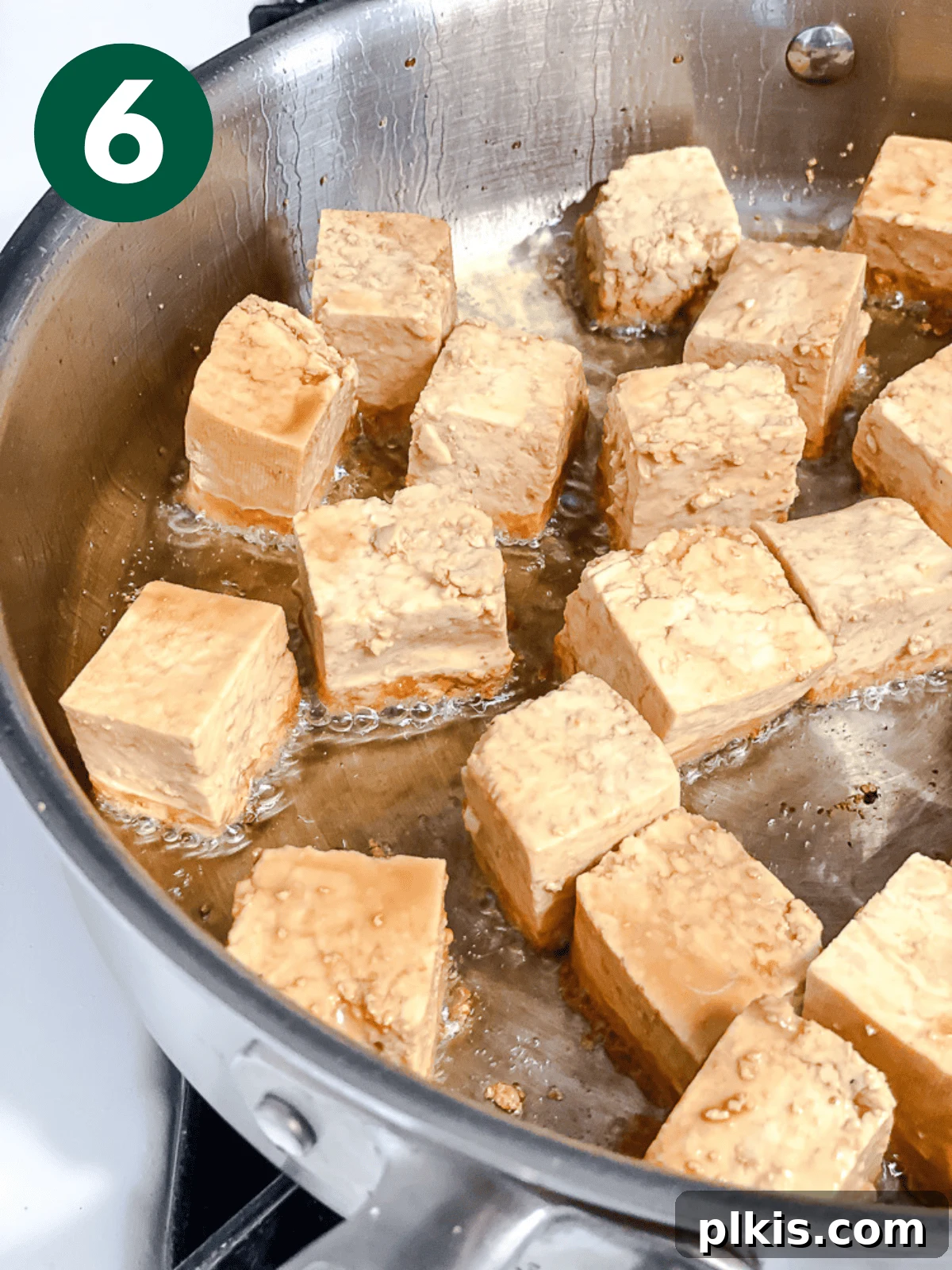 Crispy Tangy Tofu Delight 9 Tofu cubes frying in a single layer in a large metal pan until golden.