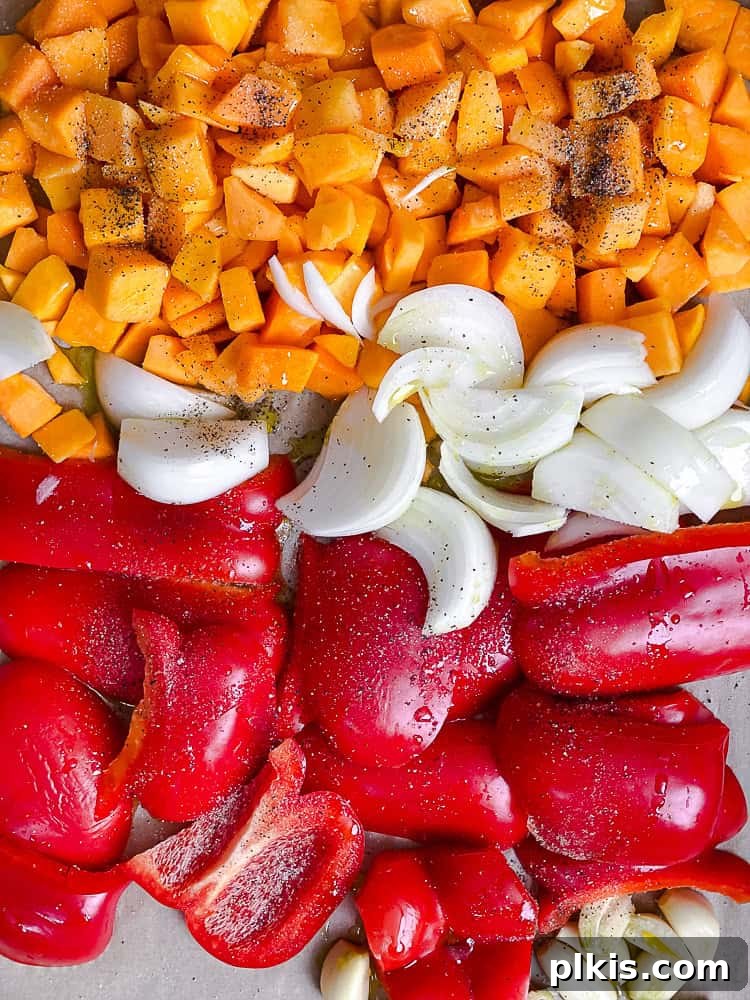 Velvety Roasted Butternut and Red Pepper Soup 5 Another process shot displaying vegetables roasting on a parchment-lined baking tray in the oven.