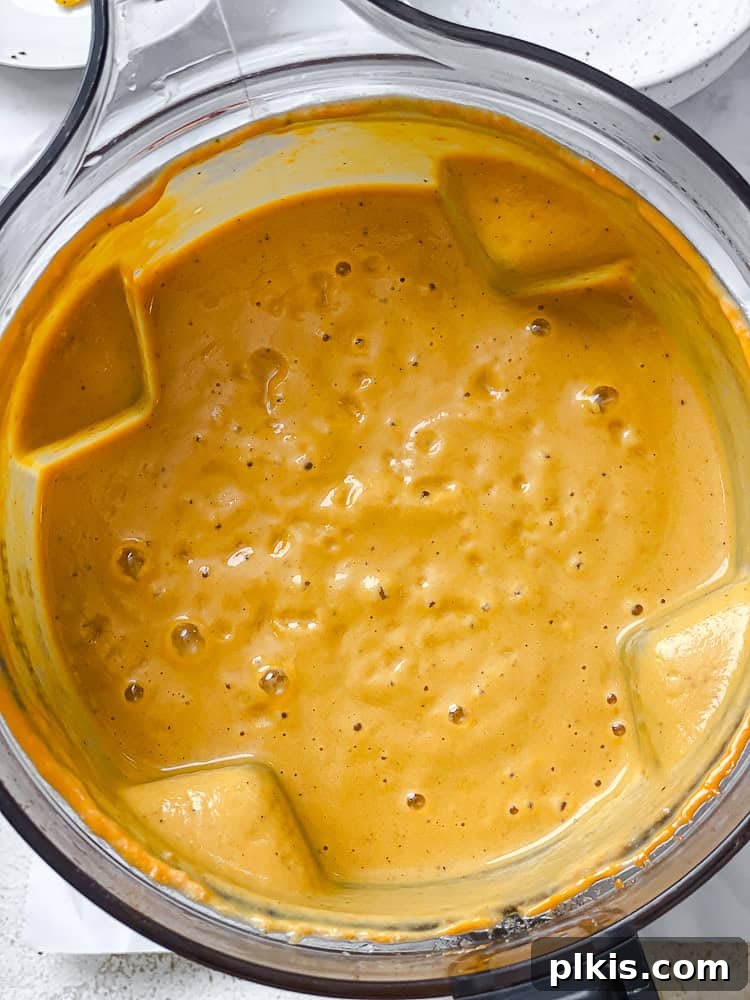 Velvety Roasted Butternut and Red Pepper Soup 8 A blender jar filled with the smooth and creamy Butternut Squash Red Pepper Soup, post-blending.