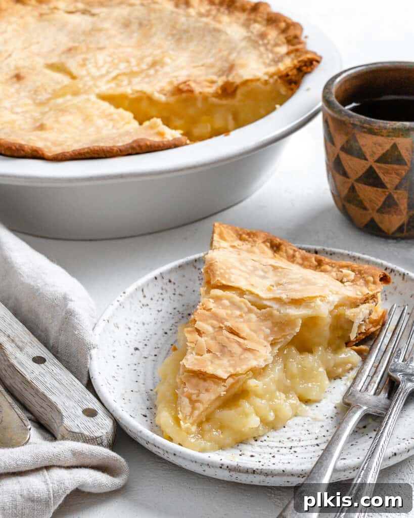 Tropical Vegan Coconut Pineapple Pie 12 A freshly baked Vegan Coconut Pineapple Pie in its dish, with one perfect slice removed and placed on a separate white plate, ready to be enjoyed.