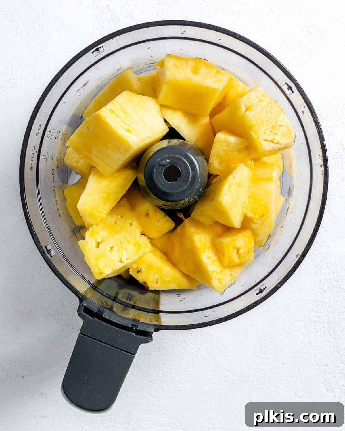 Tropical Vegan Coconut Pineapple Pie 4 Process shot of pineapple chunks being added to a blender for processing.